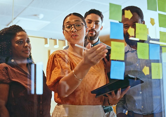 Colleagues writing sticky notes on a wall.